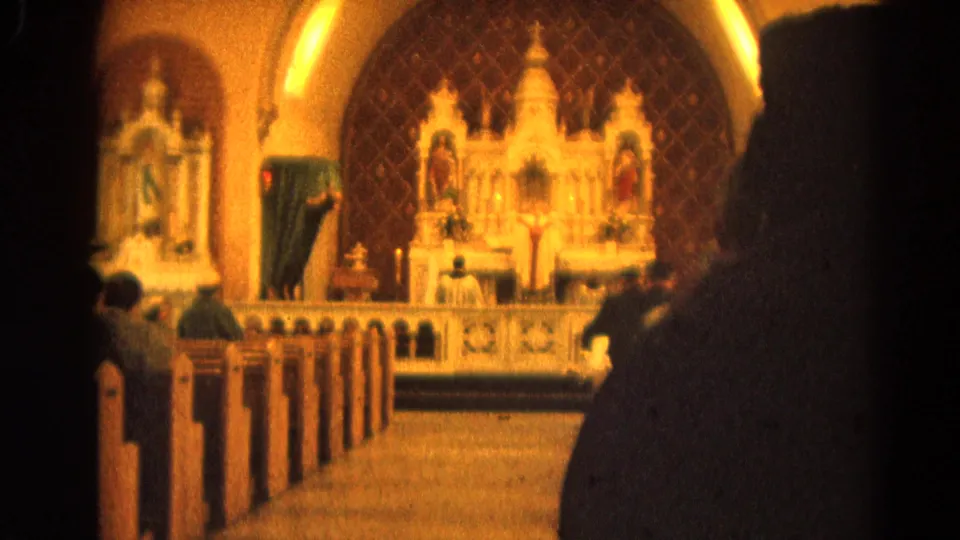 1964 home-movie view of congregants seated in pews during a Catholic service in Harvard, Illinois.