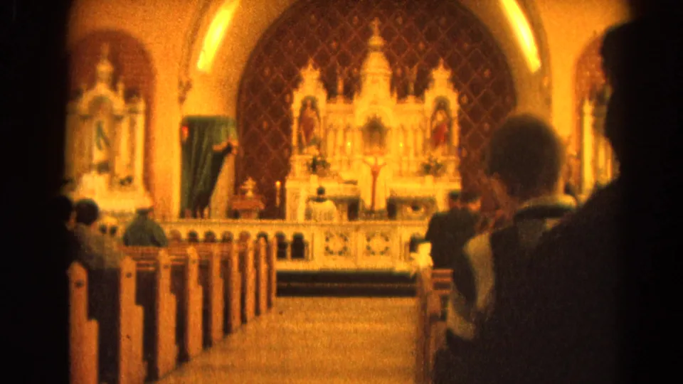 1964 8mm view from the back of a Harvard, Illinois church, with parishioners seated before an ornate Catholic altar.