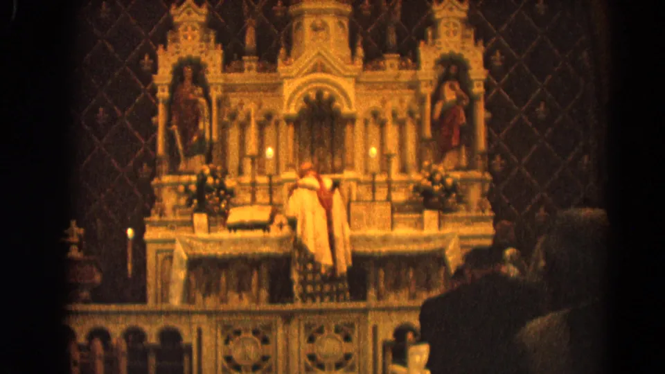 Home-movie view of a Catholic Mass in 1964 Harvard, Illinois, framed from the pews toward a decorated altar.