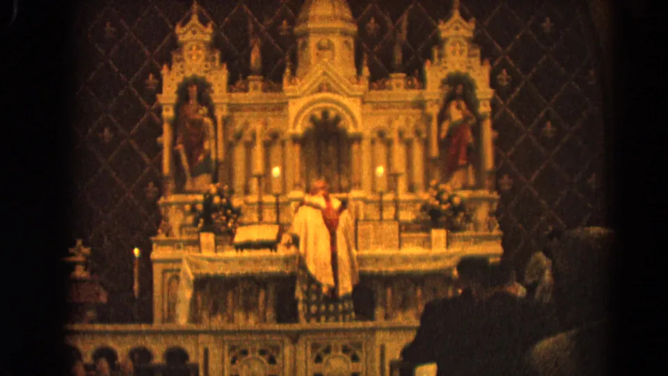 Warm 8mm frame of a Catholic priest before an ornate altar in Harvard, Illinois, with congregants visible in the foreground.