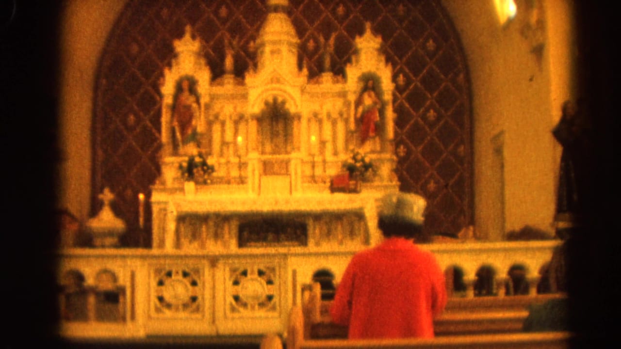 Person in a red sweater sits in a church pew facing an ornate altar.