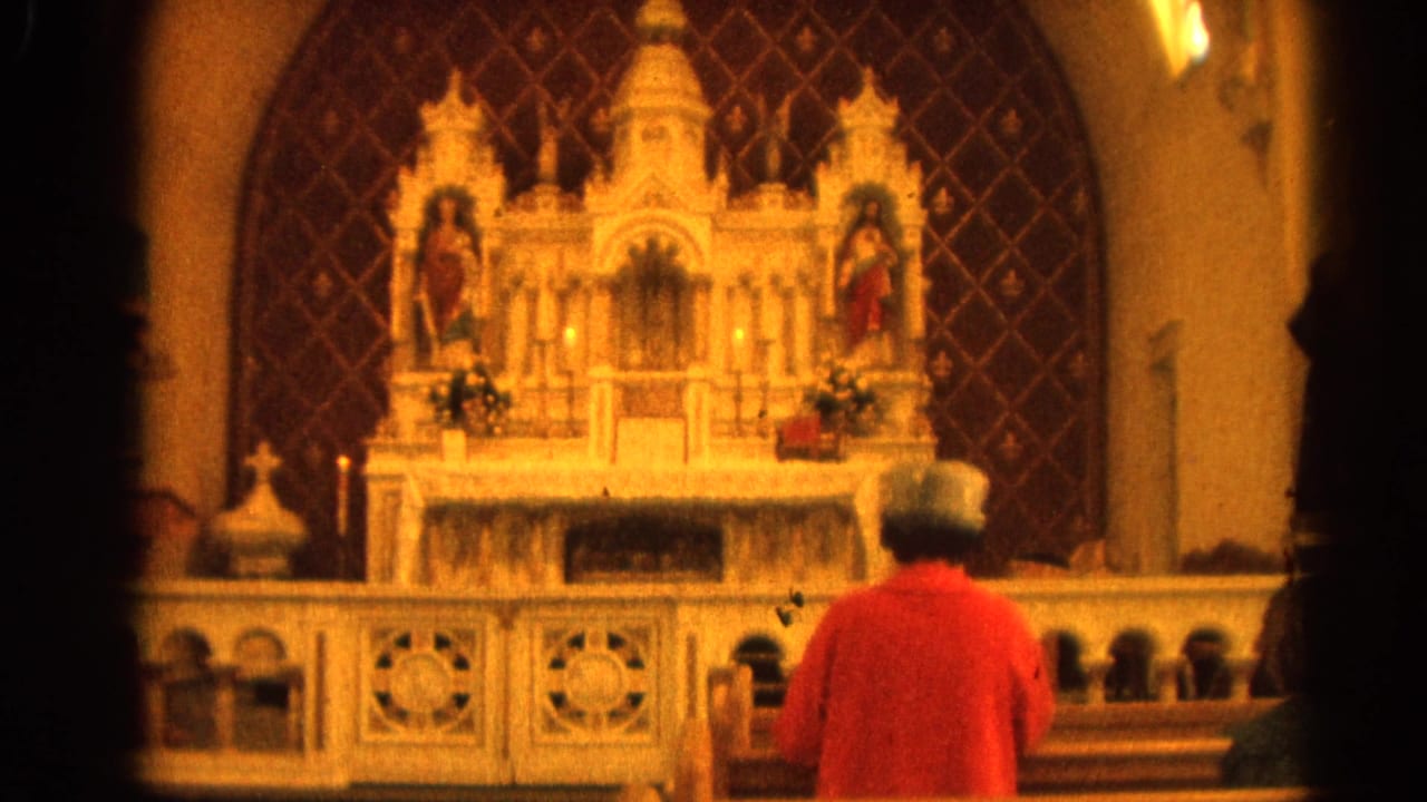 Person in a red coat praying before an ornate white church altar.