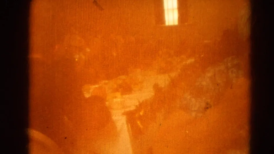 Obstructed 8mm frame with orange exposure flare and faint interior shapes from the 1964 Harvard, Illinois home-movie clip.