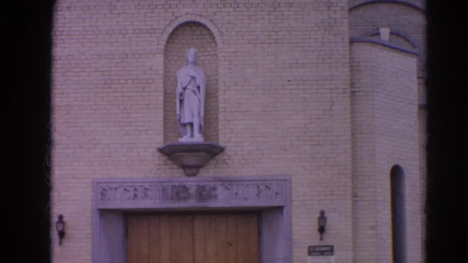 Harvard, Illinois church exterior in 1964, centered on a statue above the entrance with brickwork and a narrow vertical window nearby.