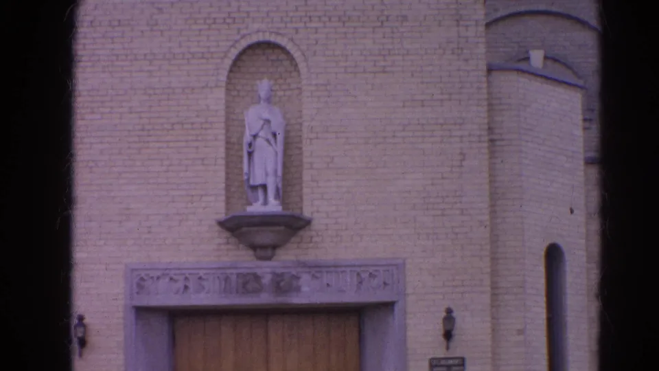 End frame of the 1964 Harvard, Illinois church facade, showing the robed statue over the doorway and rounded brick side feature.