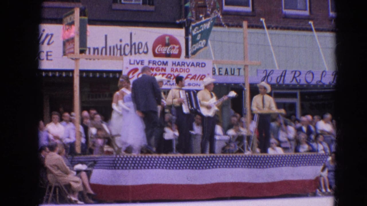 Country musicians and formal dancers appear on a 1964 Harvard, Illinois street stage with a watching crowd and visible commercial signage.