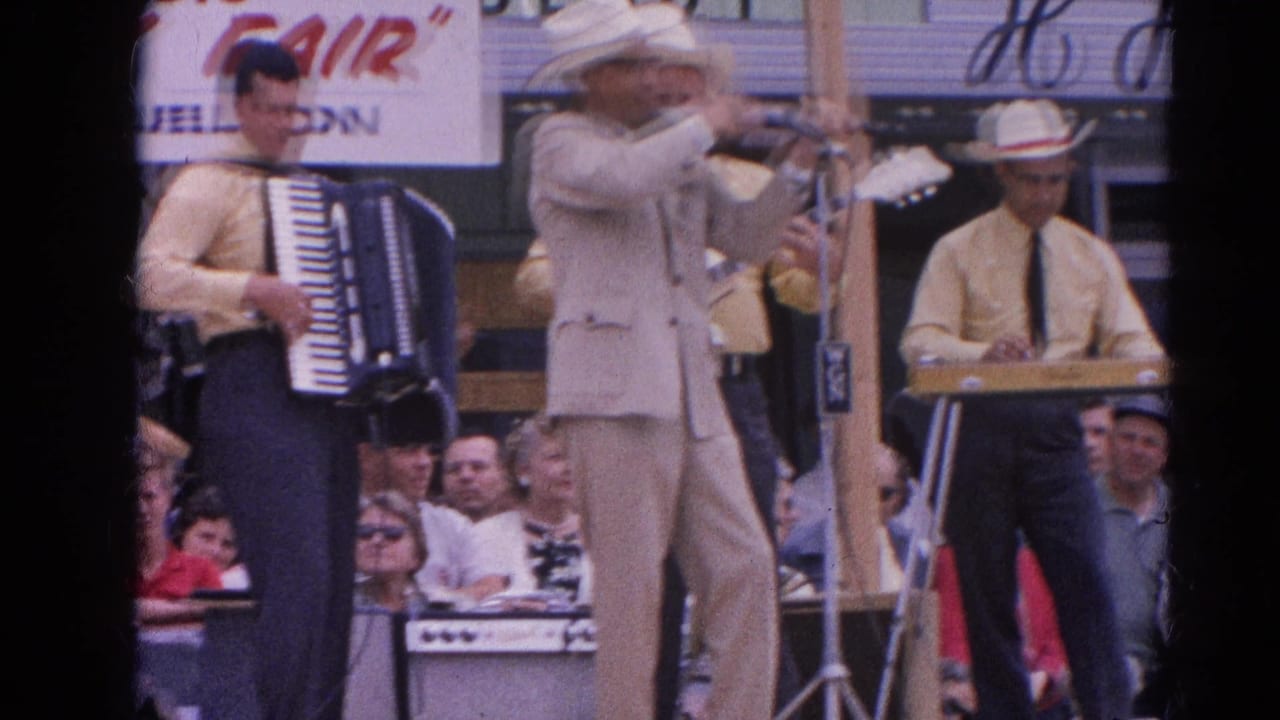 Band on outdoor fair stage with violinist, accordion player, keyboard musician, and spectators behind them.