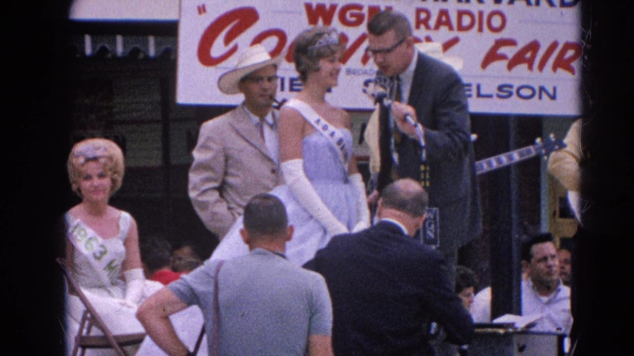A 1964 Harvard, Illinois fair stage shows a pageant contestant in a blue gown speaking with a suited interviewer near microphones and musicians.