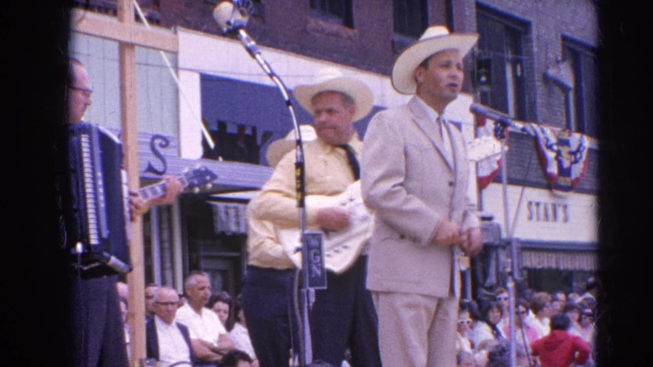 A 1964 Harvard, Illinois street-stage view shows country musicians in cowboy hats with microphone stands, guitar, accordion, and watching crowd.