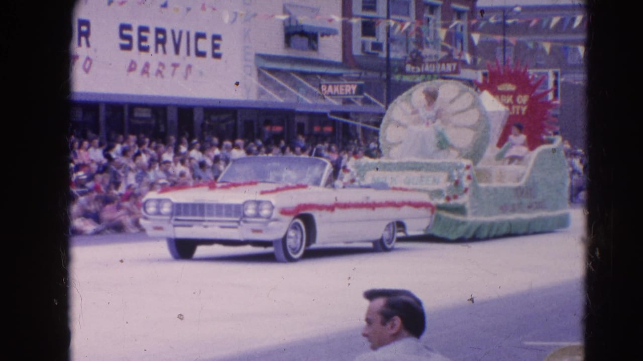 White convertible leads a Milk Queen parade float past spectators and storefronts.