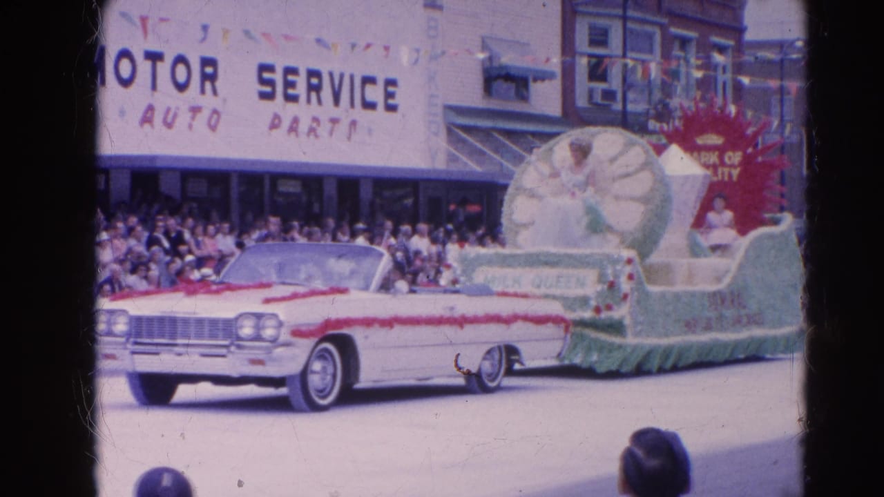 Decorated convertible and Milk Queen float pass a crowd outside Motor Service Auto Parts.