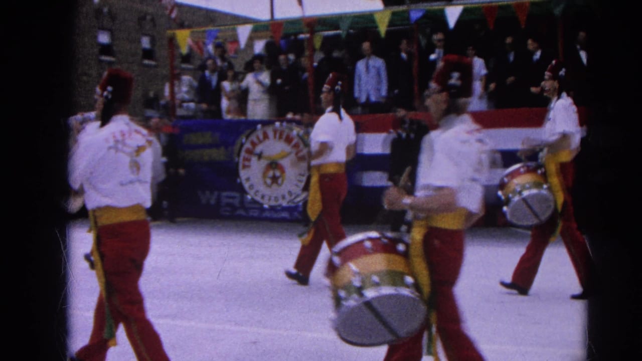 Drummers and band members march past spectators and parade bunting.