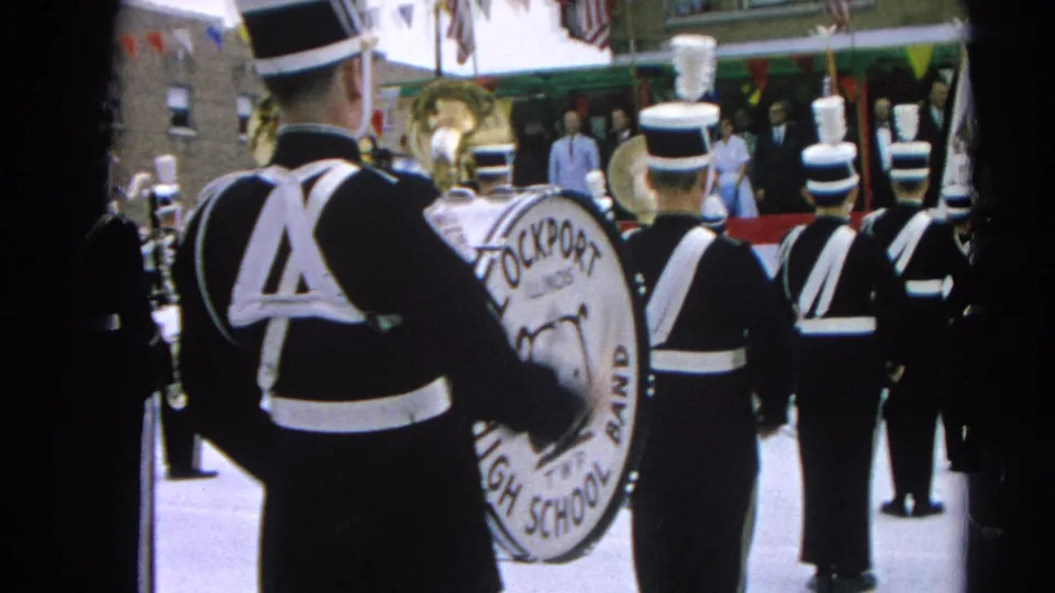 1964 Harvard, Illinois parade view from behind the Lockport High School Band, with uniforms, bass drum, flags, and bunting visible.