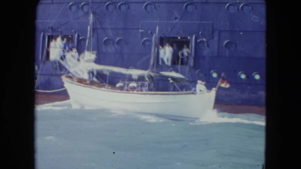 Small white boat maneuvering beside a large ocean liner in 1964 Kingston, with doorway observers, canopy, flag, and wake visible.