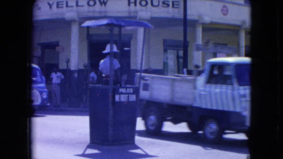 A small pickup truck crosses the Kingston street scene in front of the no-right-turn police booth and Yellow House facade.
