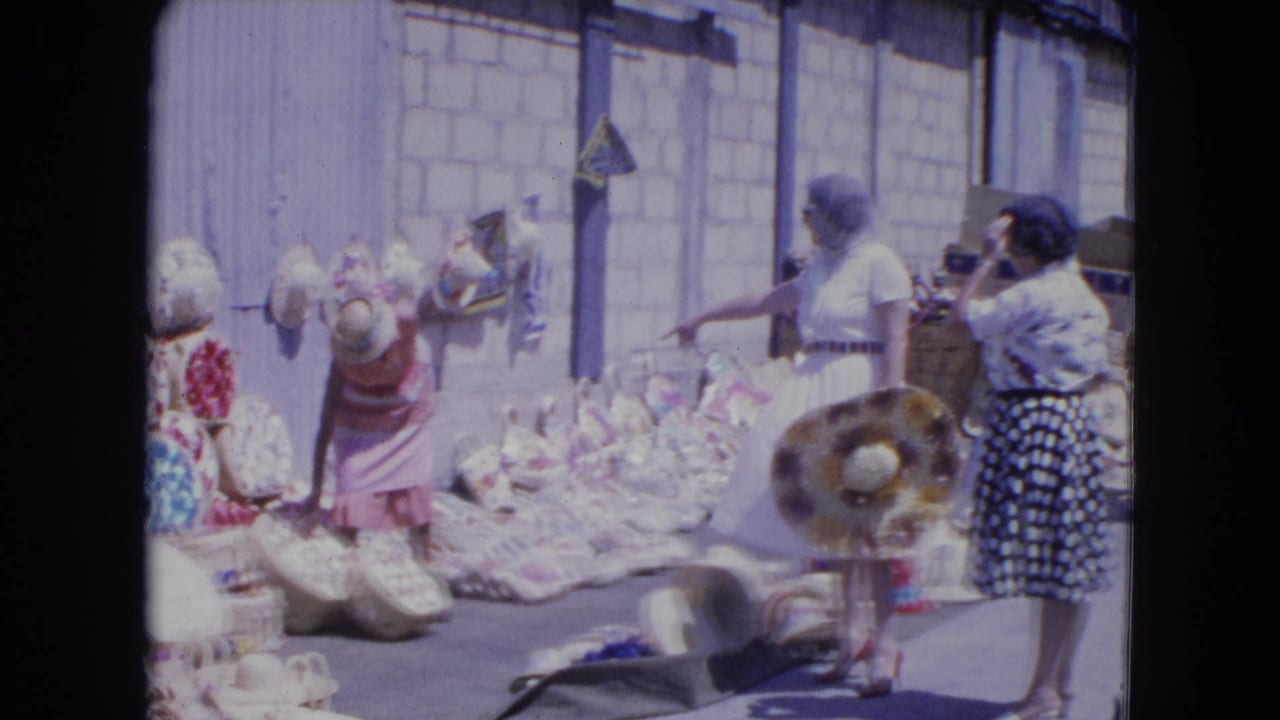 A woman points toward baskets while others stand near hats and merchandise.