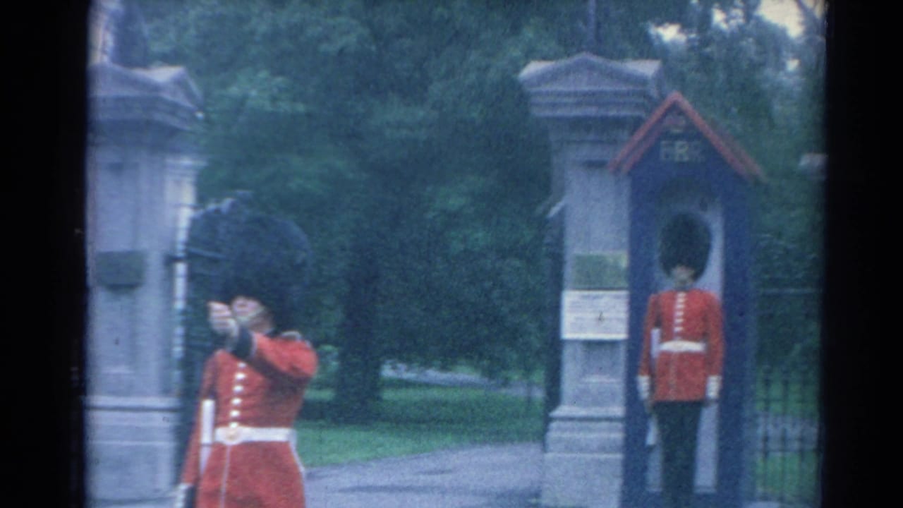 1964 London footage showing red-uniformed guards near stone gateposts and a small guard box outside a palace entrance.