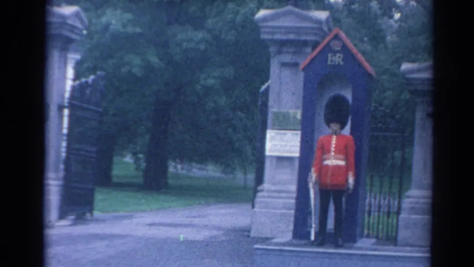 The final frame holds on the London sentry in red tunic and bearskin hat standing at post beside the ER-marked sentry box.