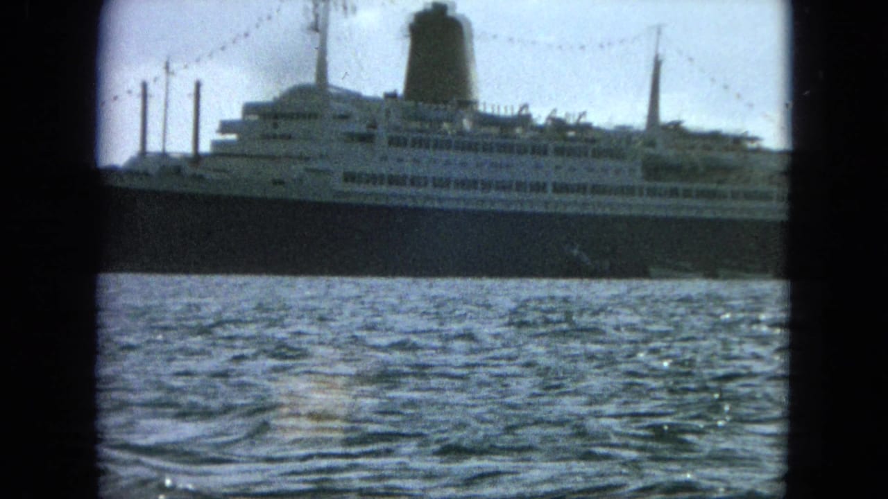Broadside view of a large ship above choppy harbor water.