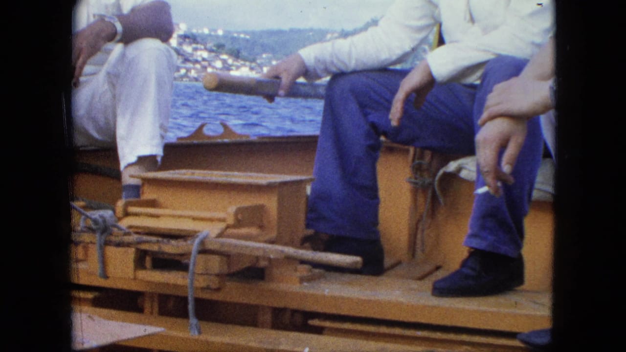 Seated adults on a wooden boat with sea and a distant coast behind them.