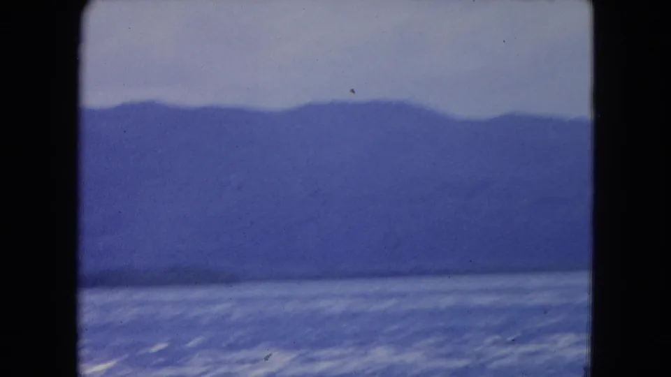 Montego Bay seascape in 1964 home-movie footage, with open water and a soft mountain ridge across the horizon.
