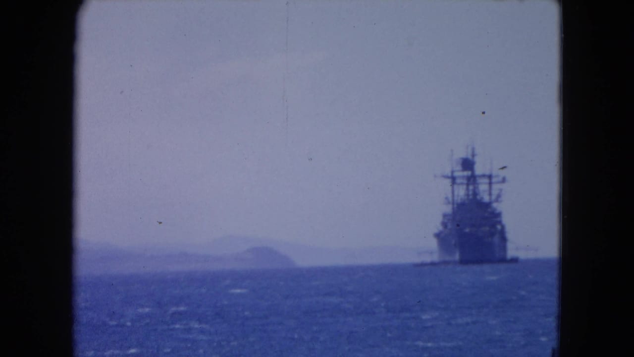 Large ship at sea with faint hills visible behind it.