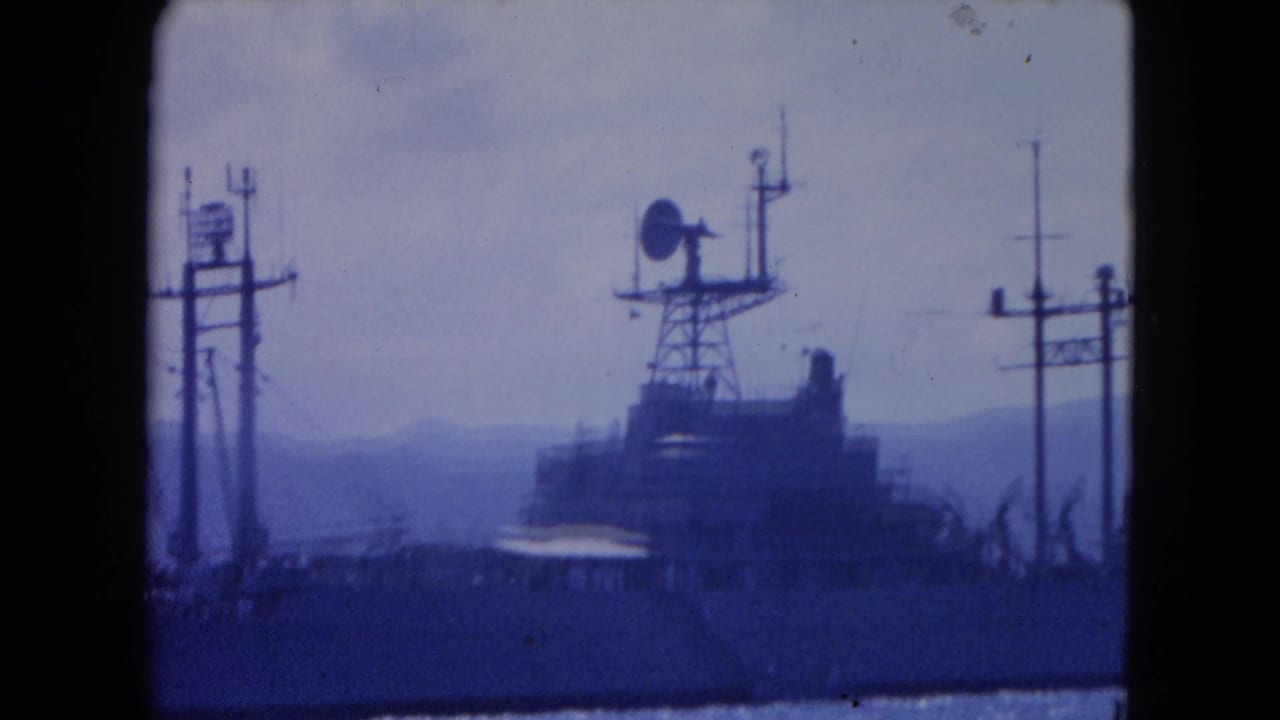 A distant radar-equipped vessel in Montego Bay harbor, filmed in 1964 with blue-tinted 8mm color and mountains behind it.