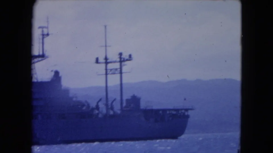Final 1964 Montego Bay frame showing the ship partly out of view, with antenna masts, harbor water, and hazy mountains visible.