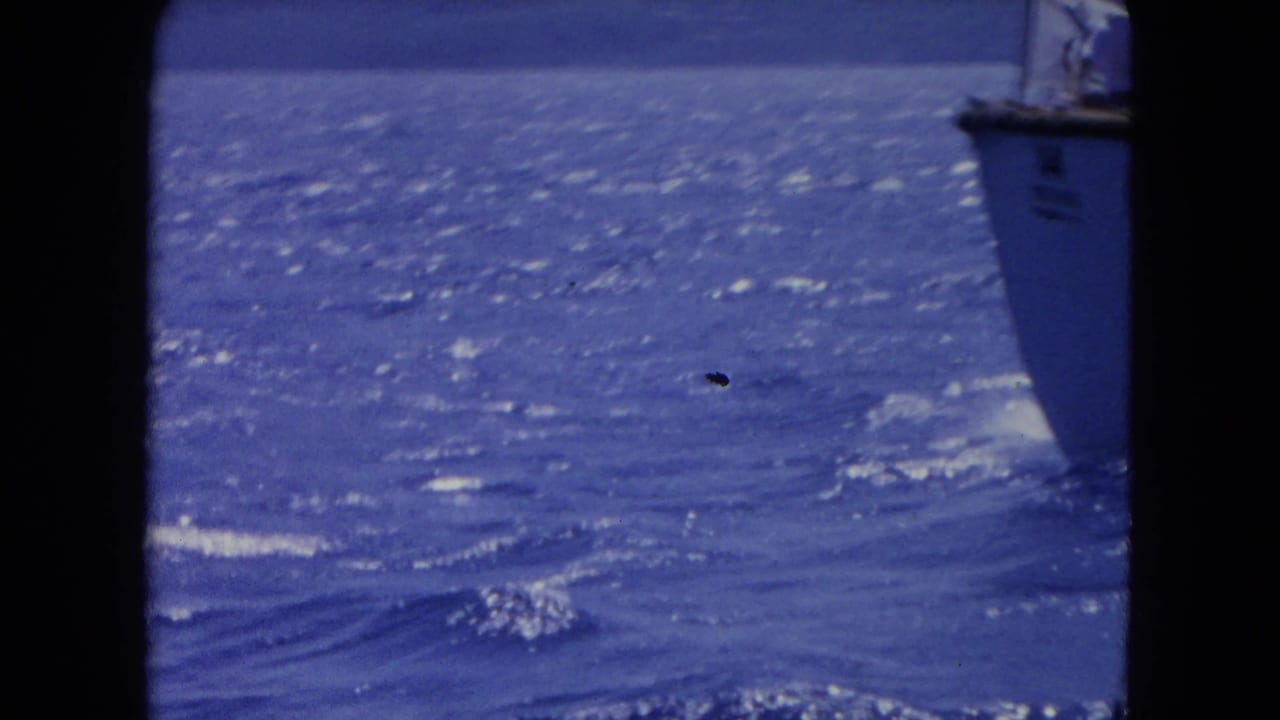 1964 Montego Bay 8mm footage showing sunlit blue water and a partially visible white boat at the edge of the frame.