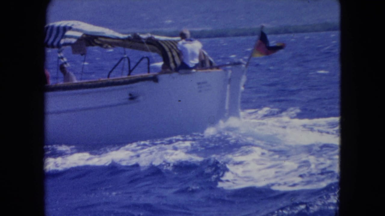 Small boat near Montego Bay with passengers under a striped canopy, a stern flag, and white wake on the sea.