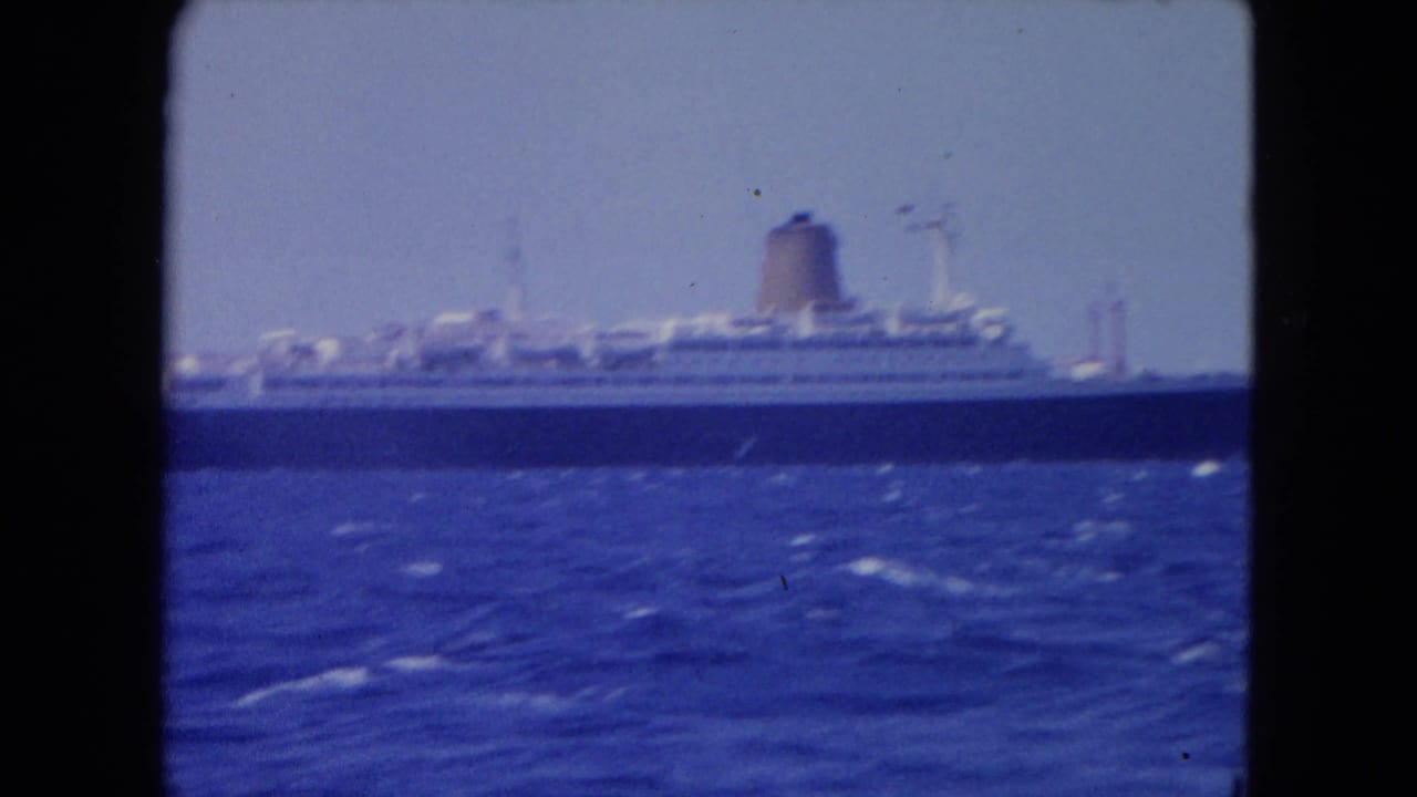 Large ocean liner crossing blue open water under a bright sky.