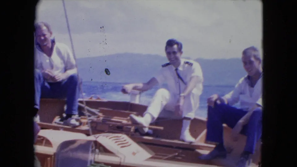 A small boat rocks on open water as three men sit or lean in the frame during this 1964 Jamaica home movie.
