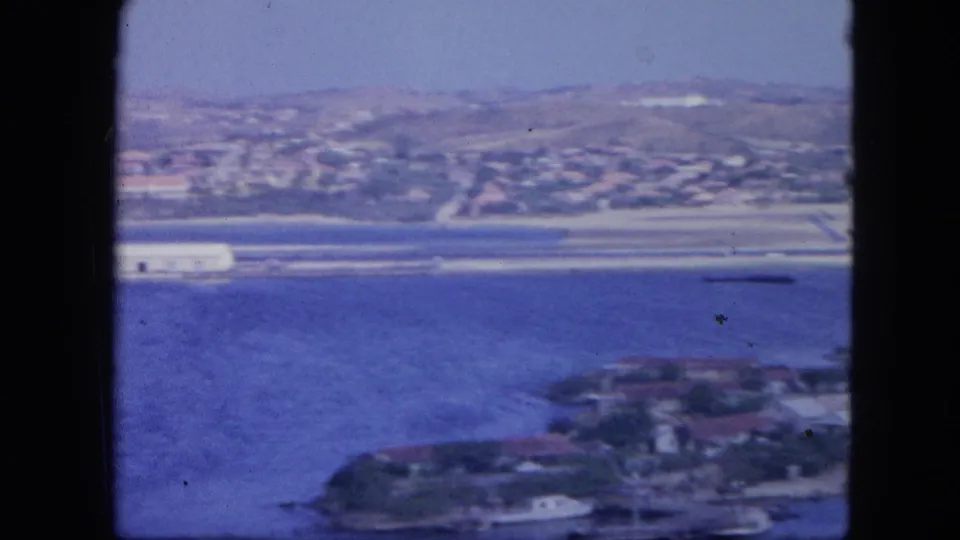 Elevated 1964 Nassau bay view with dock structures across the water and blurred waterfront buildings in the foreground.