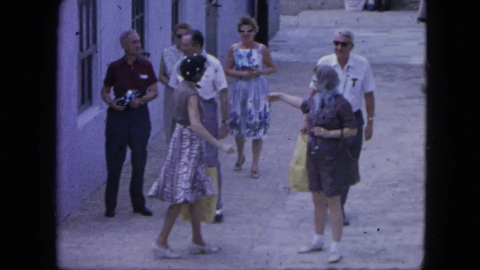 In the Nassau home-movie footage, tourists cluster in a narrow alley while one man holds a camera and women carry shopping bags.
