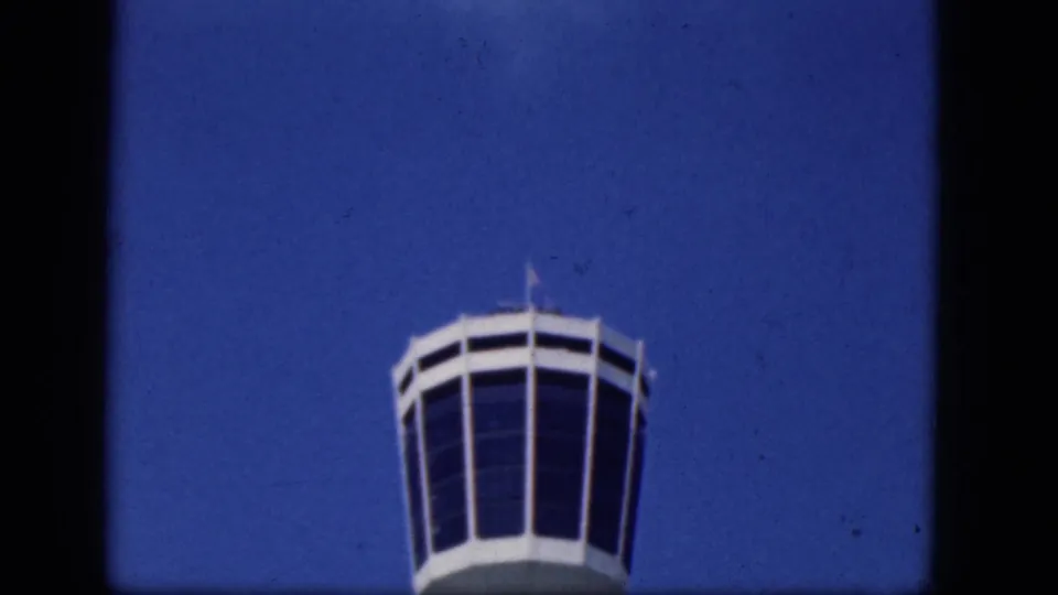 1964 Niagara Falls Canada frame showing a white airport control tower low against a broad, saturated blue sky.