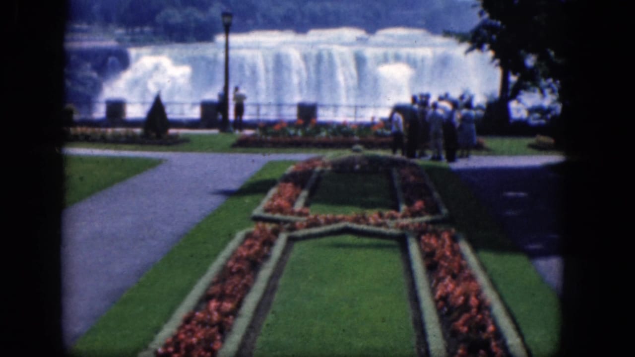 Formal flower bed and lawn leading toward visitors and a waterfall overlook.