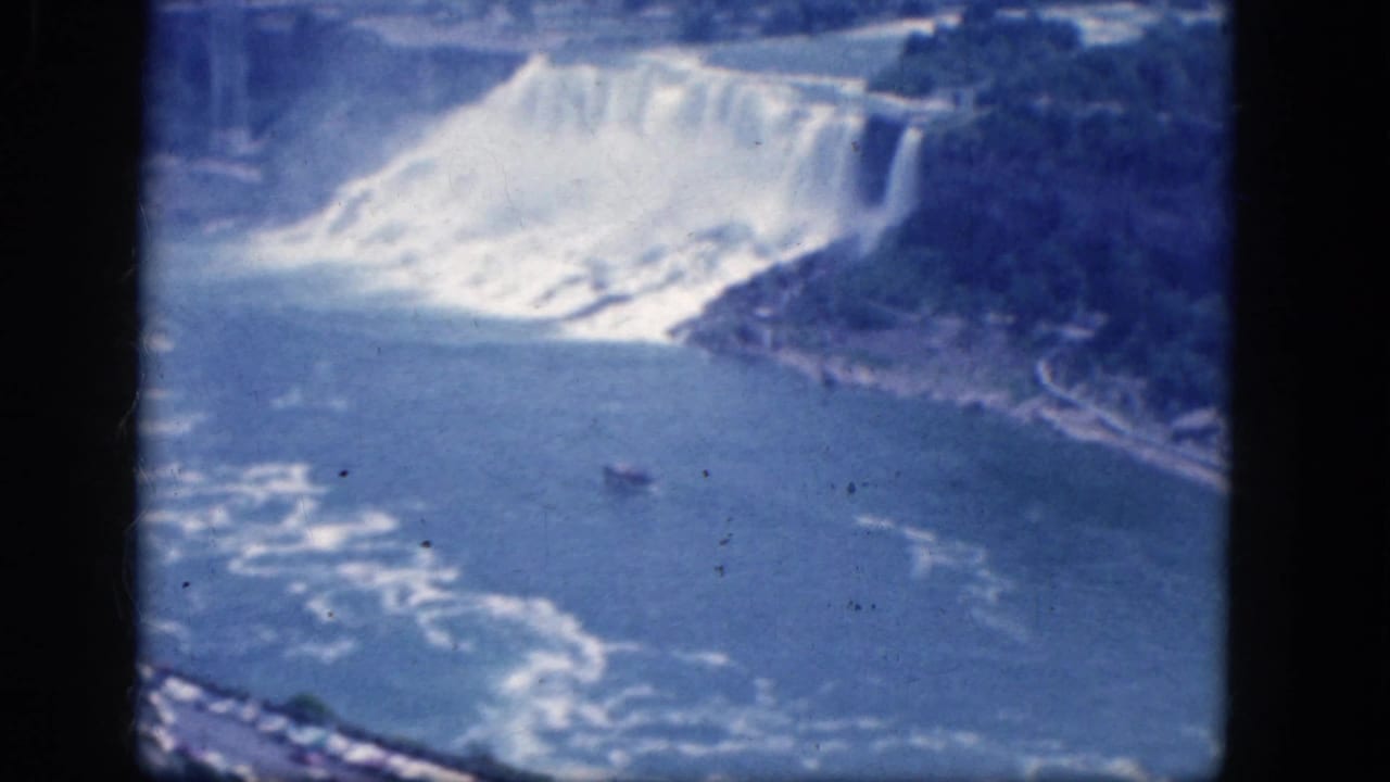 Elevated view of Niagara Falls, river, mist, shoreline, and a small boat within a dark 8mm frame border.