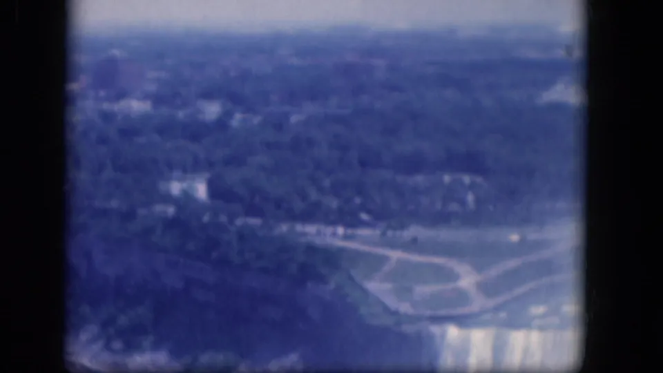 Aerial 8mm view over Niagara Falls parkland, with paths, water, tree cover, and the waterfall edge entering the lower frame.
