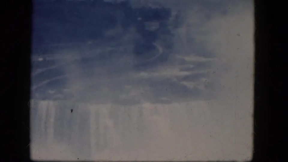 1964 8mm home-movie frame showing mist, blue-gray water, and the upper edge of Horseshoe Falls in Canada.