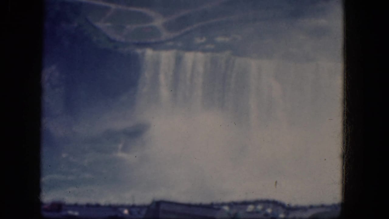 Canadian Niagara Falls appears through soft 8mm focus, with falling water, heavy mist, and a low shoreline visible beneath.