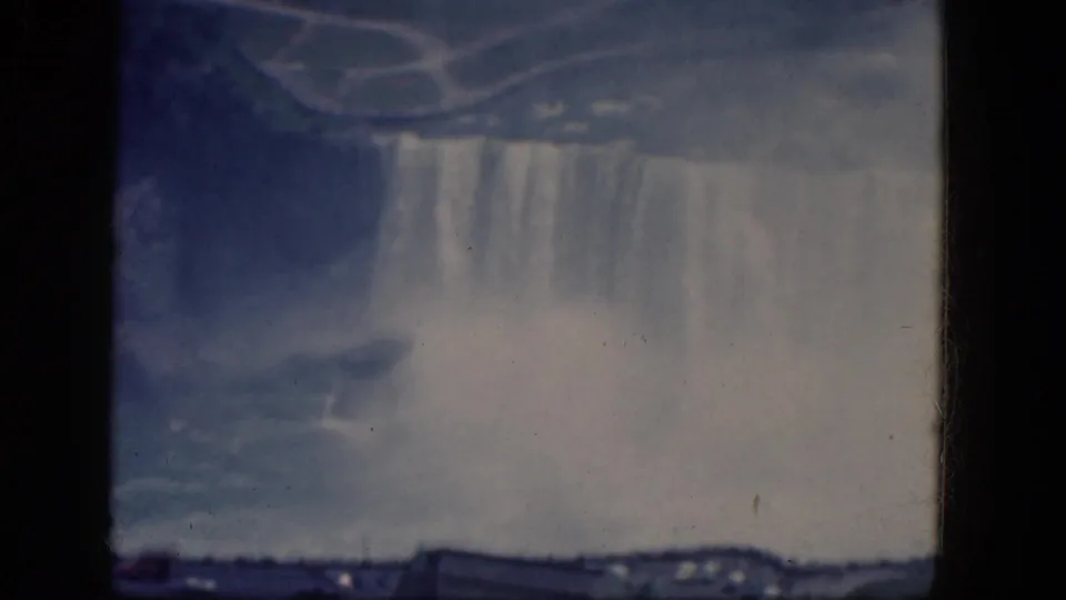 Canadian Niagara Falls appears through soft 8mm focus, with falling water, heavy mist, and a low shoreline visible beneath.