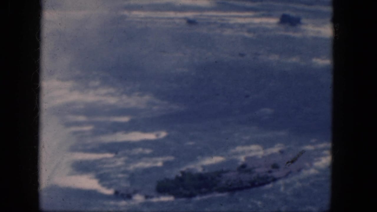 1964 Niagara Falls, Canada frame with blue water, bright reflections, and a dark rocky shoreline area.