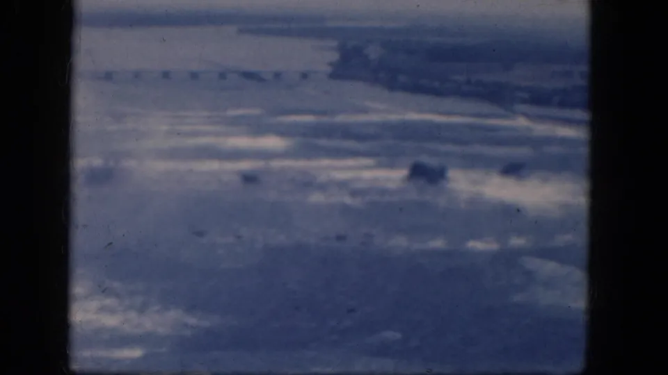 1964 8mm home-movie frame from Niagara Falls, Canada, showing a hazy elevated view over water, mist, and distant shoreline.