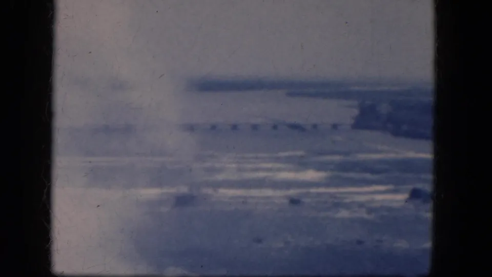 Faded 8mm frame from the Niagara Falls, Canada area, showing a hazy overlook with water, distant land, and gate-edge framing.