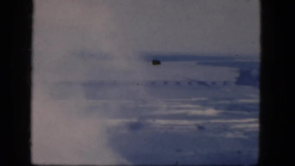 End frame of a 1964 8mm Niagara Falls, Canada overlook, with blurred water, shoreline, haze, and visible film-gate borders.