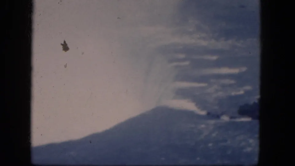 Final 8mm frame of Niagara Falls, Canada, with mist spreading over blue water and a rocky island clipped at the right edge.