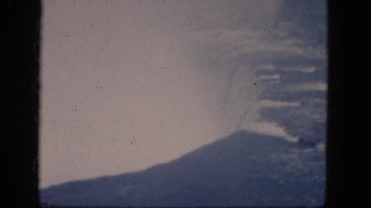 Hazy sky and dark hillside seen through an 8mm film frame.