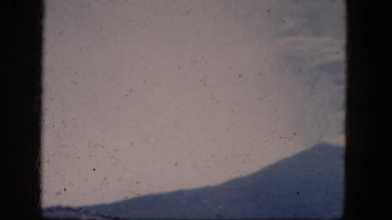 Grainy 1964 8mm frame showing a distant hillside under pale haze near Niagara Falls, Canada.