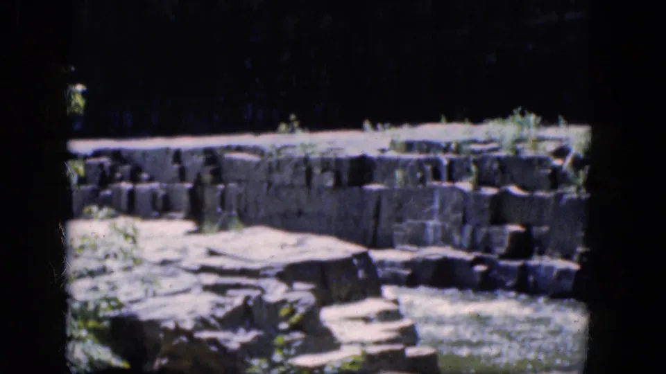 1964 8mm view of fast water and stone shelves at Niagara Falls, Canada, framed by dark film edges.