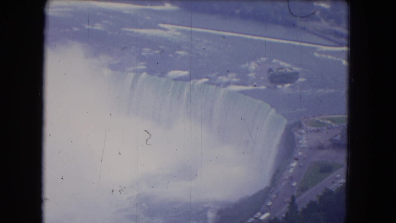 Aerial view of Niagara Falls with mist, river, snow or ice, and dark film borders.